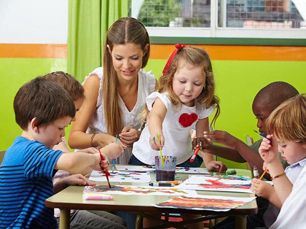 Several kids painting around a table in Oakland extended care program