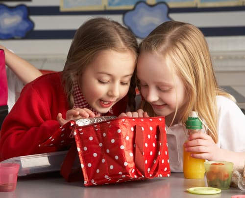 2 girls looking into lunchbox