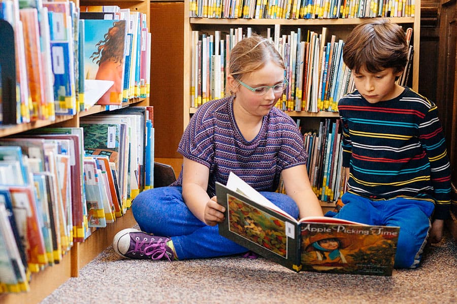 Kids sitting on library floor, looking at books together
