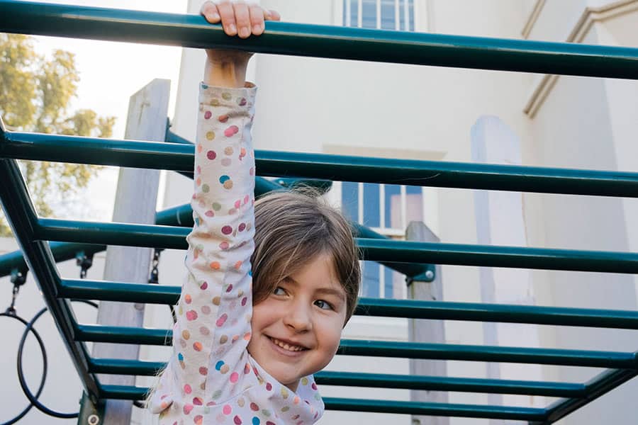 Kid playing on bars outside