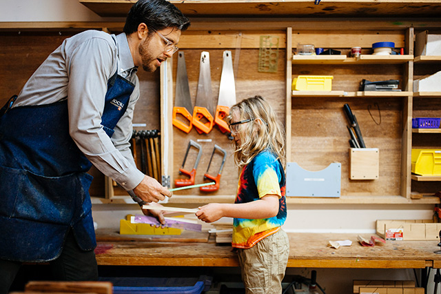 Woodshop teacher and elementary student working together
